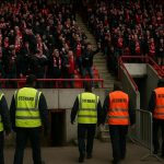 Stewards bewaken de spelerszone in het stadion van Standard Luik na onrust op Sclessin