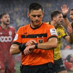 Scheidsrechter controleert zijn horloge tijdens discussie over tijdrekken