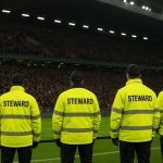 Sfeerbeeld in een Belgisch voetbalstadion tijdens een wedstrijd, met nadruk op veiligheid en zonder pyrotechnisch materiaal.