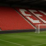 Lege stadiontribune met stoelen in clubkleuren, zonder herkenbare personen.