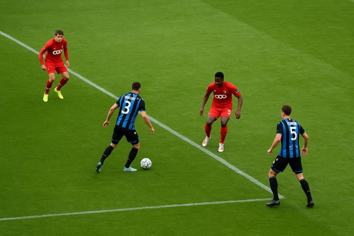Distant match action met spelers van Club Brugge in beweging, zonder herkenbare gezichten.
