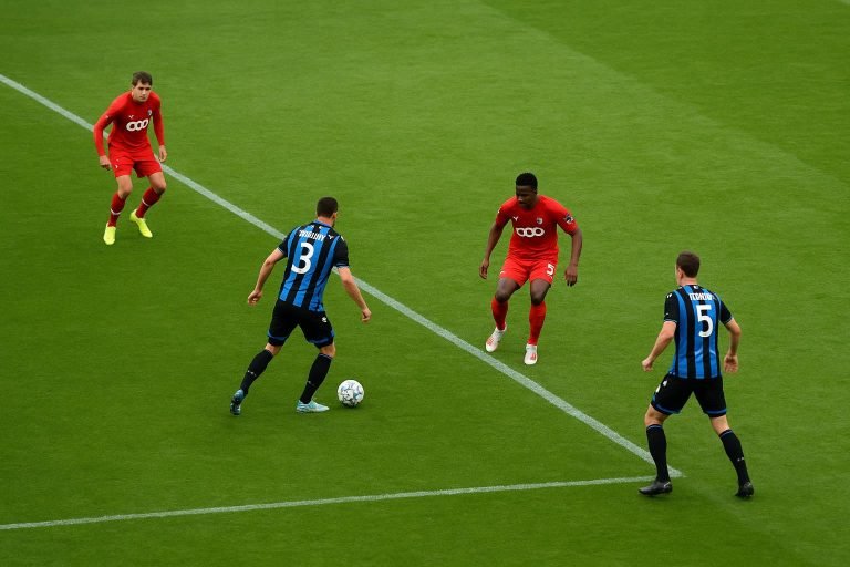 Distant match action met spelers van Club Brugge in beweging, zonder herkenbare gezichten.