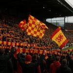 Supporters van KV Mechelen in het stadion tijdens een wedstrijd, met focus op sfeer en clubkleuren