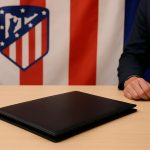 Een transferscène in het Estadio Metropolitano bij Atlético Madrid, met een contractmap en clubkleuren zichtbaar.