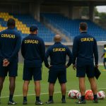 Curaçao-staf op het trainingsveld, met focus op coachingzone zonder herkenbare gezichten