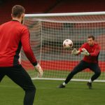Doelmannen van Manchester United op training met keepershandschoenen en doelen op de achtergrond.