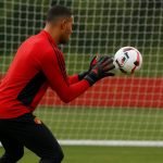 Doelman in trainingscontext bij Manchester United, met focus op handschoenen en doelnet