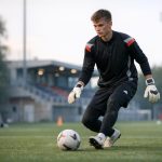 Jonge doelman die mee opbouwt en een korte pass inspeelt onder druk