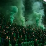 Sfeerbeeld in een stadionvak van Lommel SK met rook door pyrotechniek, zonder herkenbare gezichten.
