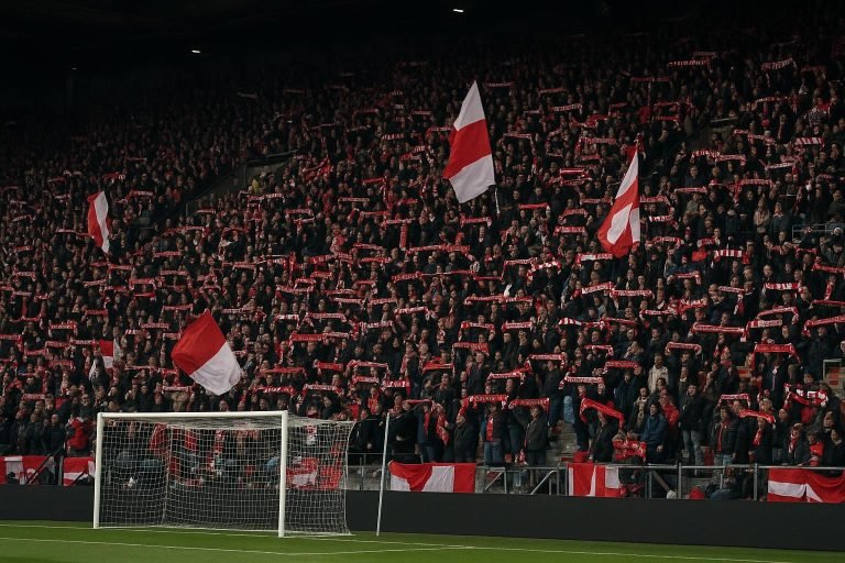 Supporters op de tribune tijdens een wedstrijd in België, als beeld bij financiële druk in het profvoetbal