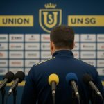 David Hubert langs de zijlijn tijdens een wedstrijd van Union SG, met het stadion op de achtergrond.
