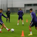 Spelers van RSC Anderlecht op training met staf in de achtergrond, zonder herkenbare gezichten