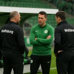 Sfeerbeeld van de technische staf van VfL Wolfsburg tijdens een moment van overleg langs het veld.