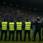 Stewards en politie vormen een menselijke barrière op het veld na Rangers tegen Celtic