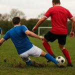 Actiebeeld van een sliding in het amateurvoetbal op een lokaal veld, zonder herkenbare gezichten.