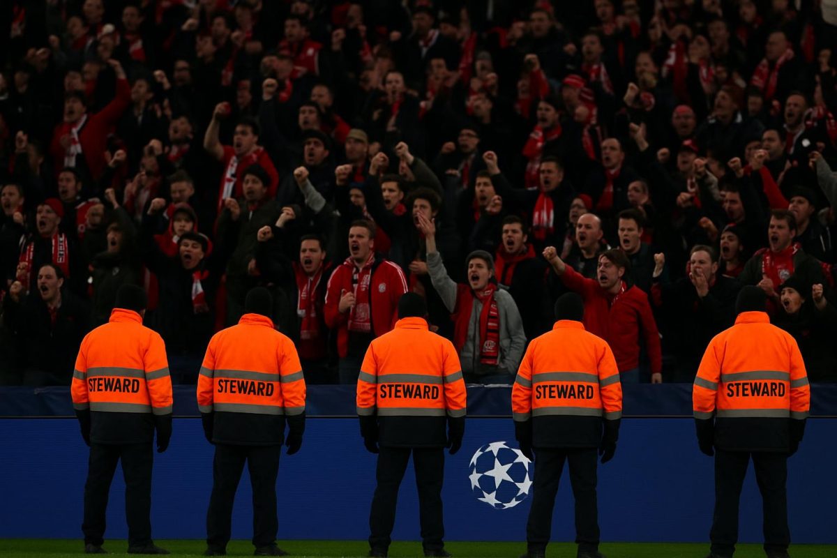 Stewards en supporters aan de reclameborden na onrust tijdens Bayern tegen Real Madrid
