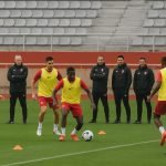 Sfeerbeeld van een trainingsmoment bij AS Monaco, met stafleden langs de zijlijn in het stadion.