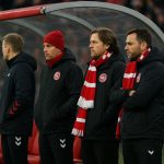 Sfeerbeeld van de Deense nationale ploeg langs de zijlijn in een stadion, zonder herkenbare gezichten.
