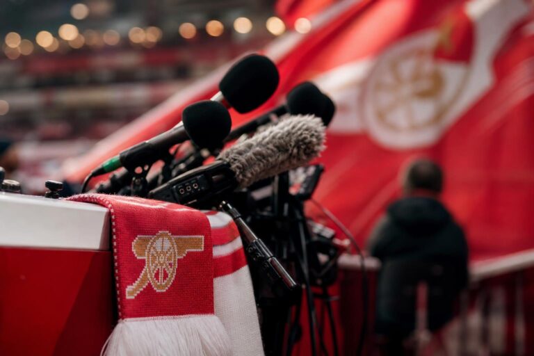 Arsenal-sfeer met persmicrofoons en stadionlichten rond het voetbalverleden van Remco Evenepoel
