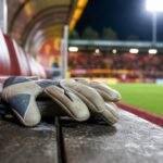 Keepershandschoenen op een bank bij KV Mechelen als symbool voor onzekerheid onder de lat