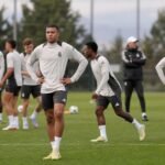 Spelers van Real Madrid op training in een gespannen sfeer, gefotografeerd vanop afstand zonder herkenbare gezichten.