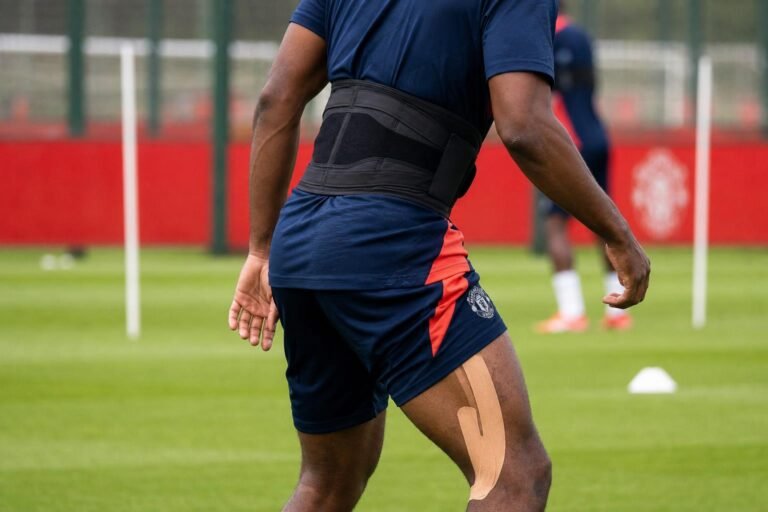 Sfeerbeeld van een speler in Manchester United-trainingskledij tijdens een revalidatiemoment op het oefenveld