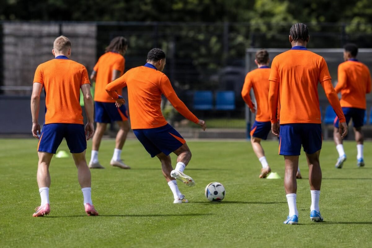 Training van Oranje op een oefenveld, met spelers in oranje tenue zonder herkenbare gezichten