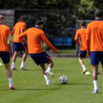 Training van Oranje op een oefenveld, met spelers in oranje tenue zonder herkenbare gezichten