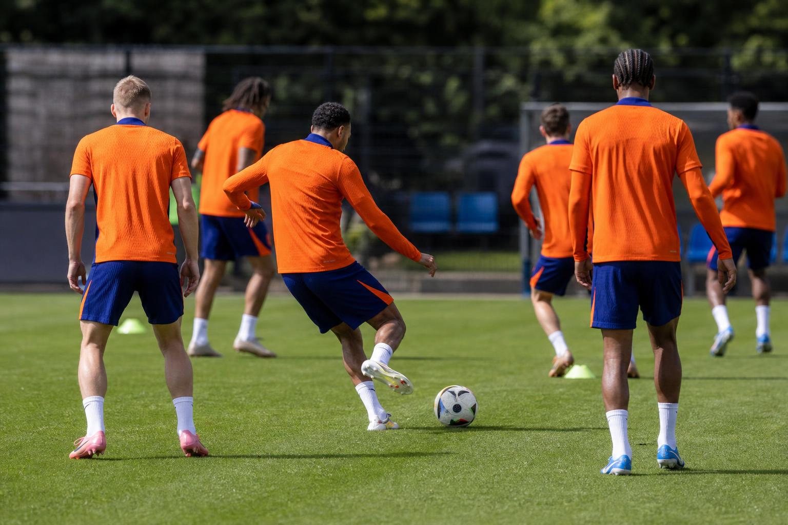 Training van Oranje op een oefenveld, met spelers in oranje tenue zonder herkenbare gezichten