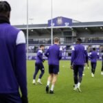 Trainingbeeld in het Lotto Park met een Anderlecht-speler op de achtergrond, zonder herkenbare gezichten