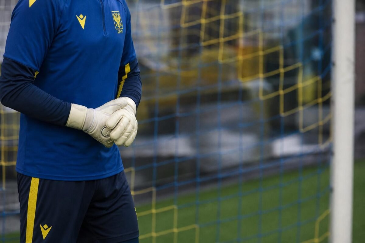 Een doelman van STVV op training aan het doel met keepershandschoenen