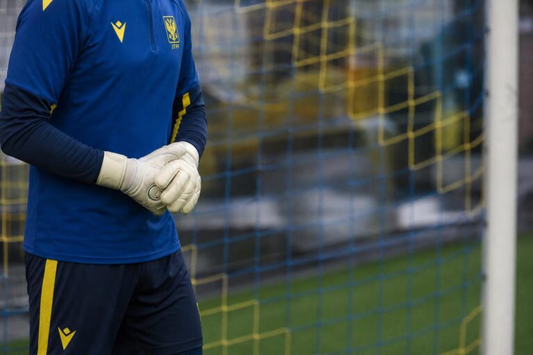 Een doelman van STVV op training aan het doel met keepershandschoenen