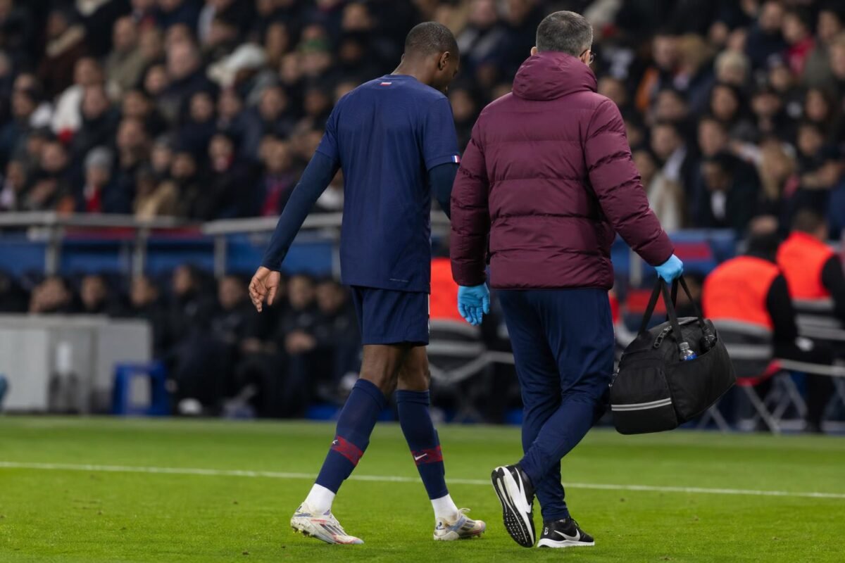 Een PSG-speler verlaat het veld na een vroeg schrikmoment, met stafleden op de achtergrond.