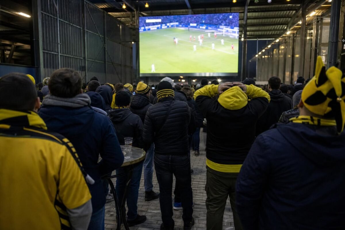 Supporters van STVV volgen een Europese wedstrijd op een groot scherm.