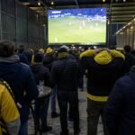 Supporters van STVV volgen een Europese wedstrijd op een groot scherm.