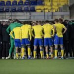 Sfeerbeeld van STVV-spelers in geel-blauw tijdens een wedstrijd, met focus op het teammoment zonder herkenbare gezichten.