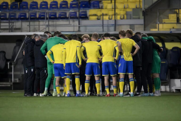Sfeerbeeld van STVV-spelers in geel-blauw tijdens een wedstrijd, met focus op het teammoment zonder herkenbare gezichten.
