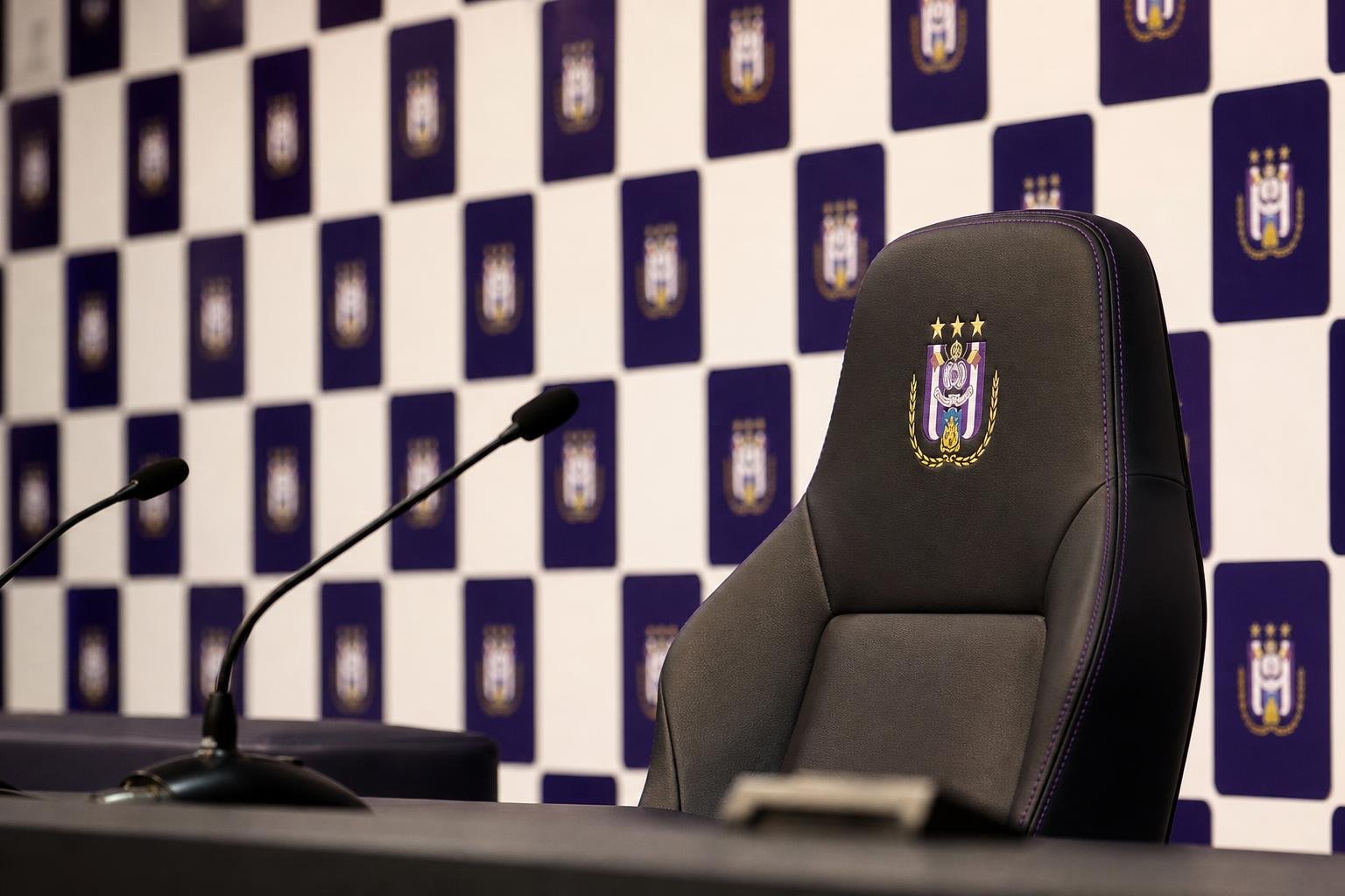 Lege trainersstoel en microfoons in een gespannen Anderlecht-perscontext