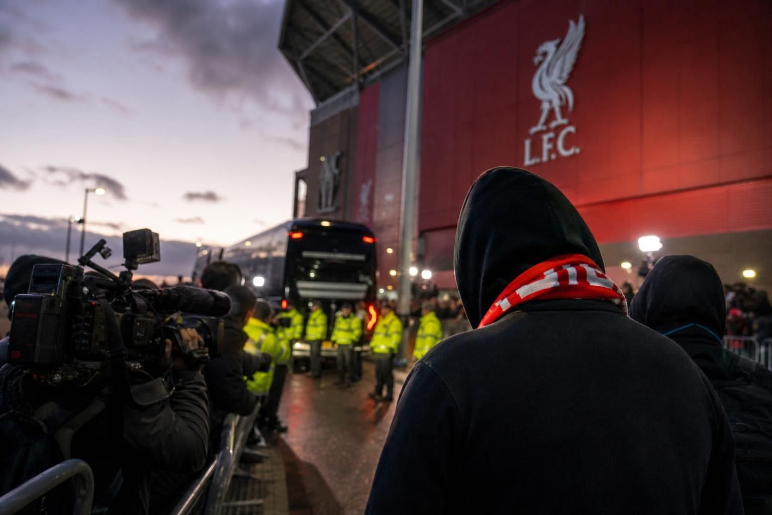 Transfercontext rond Liverpool met rode sjaals en perscamera's aan een stadion.