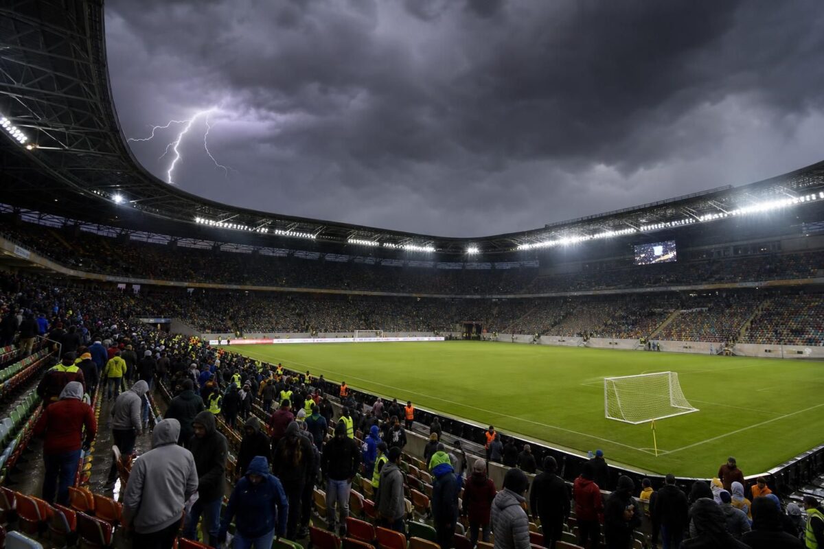 Een voetbalstadion onder dreigende onweerslucht tijdens een onderbroken wedstrijd.