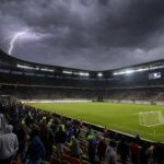 Een voetbalstadion onder dreigende onweerslucht tijdens een onderbroken wedstrijd.