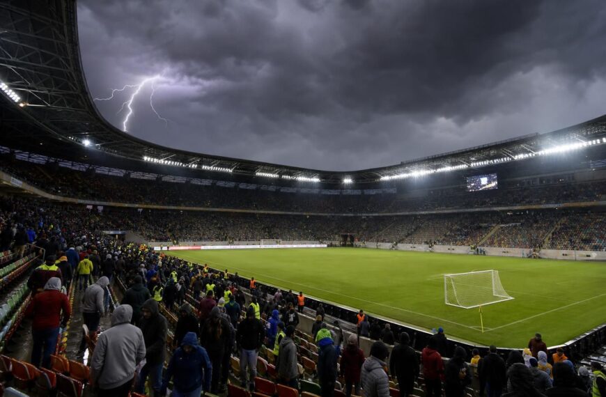 Een voetbalstadion onder dreigende onweerslucht tijdens een onderbroken wedstrijd.