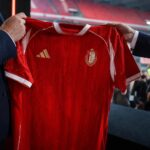 Een rood Standard Luik-thuisshirt wordt gepresenteerd in een clubcontext zonder herkenbare gezichten.