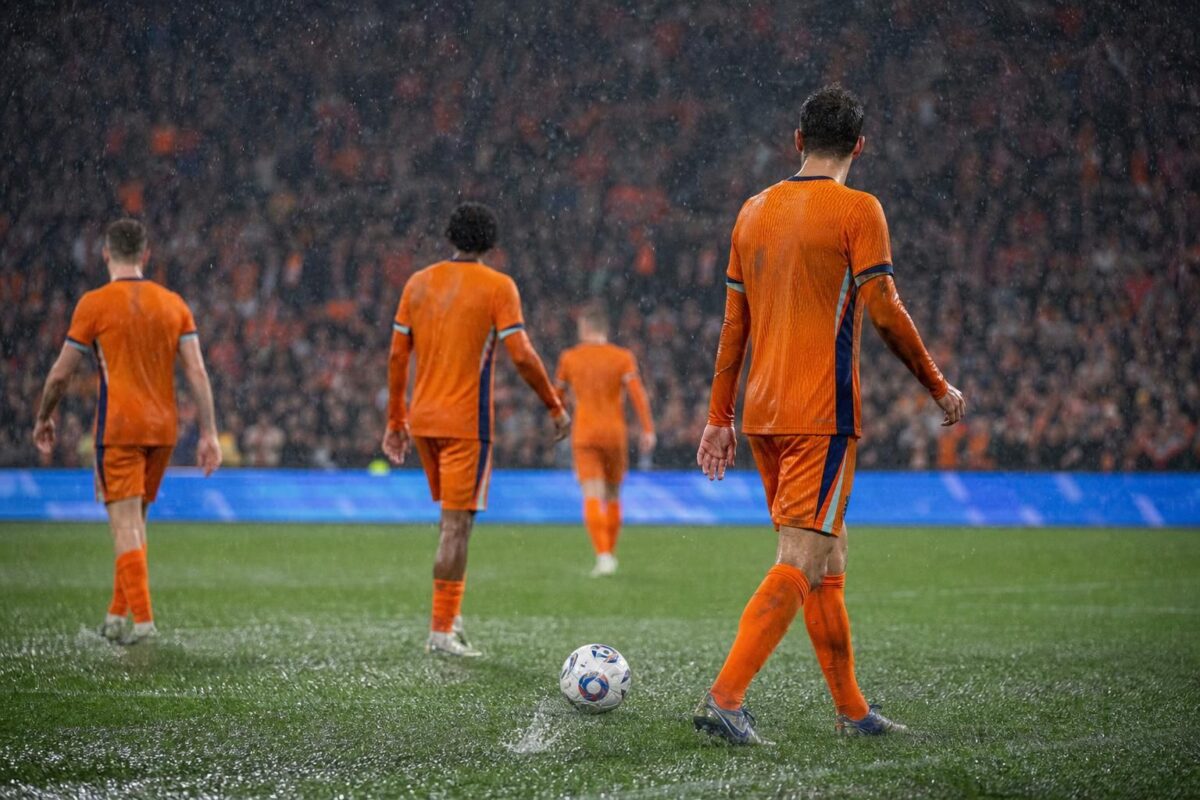 Spelers van Nederland en Tunesië in de regen tijdens een WK-wedstrijd in Kansas City