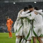 Algerijnse spelers vieren een late goal tegen Nederland in een regenachtige De Kuip zonder herkenbare gezichten