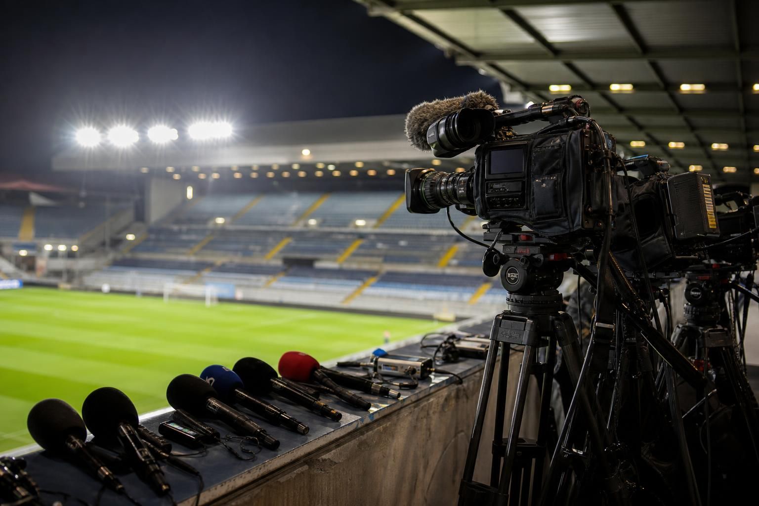 Televisiecamera's en persmateriaal in een Belgisch voetbalstadion tijdens een gespannen rechtenconflict