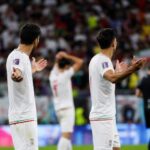 Iraanse spelers reageren gefrustreerd in een WK-stadion na een beslissend moment.