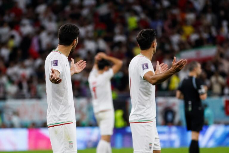 Iraanse spelers reageren gefrustreerd in een WK-stadion na een beslissend moment.