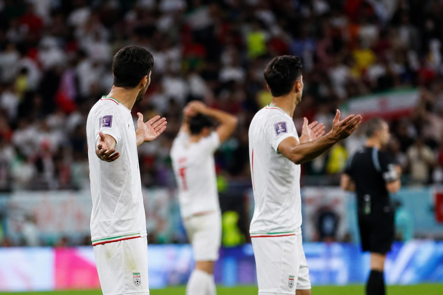 Iraanse spelers reageren gefrustreerd in een WK-stadion na een beslissend moment.