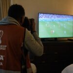 Een ploegfotograaf richt zijn camera op een televisiescherm tijdens een WK-wedstrijd van Senegal.